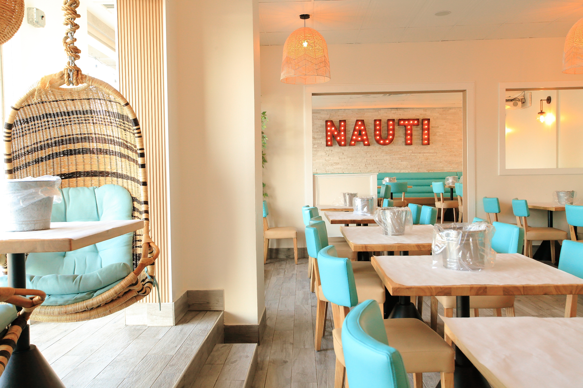Bright, beachy Nauti Crab dining room with turquoise seating and rattan accents
